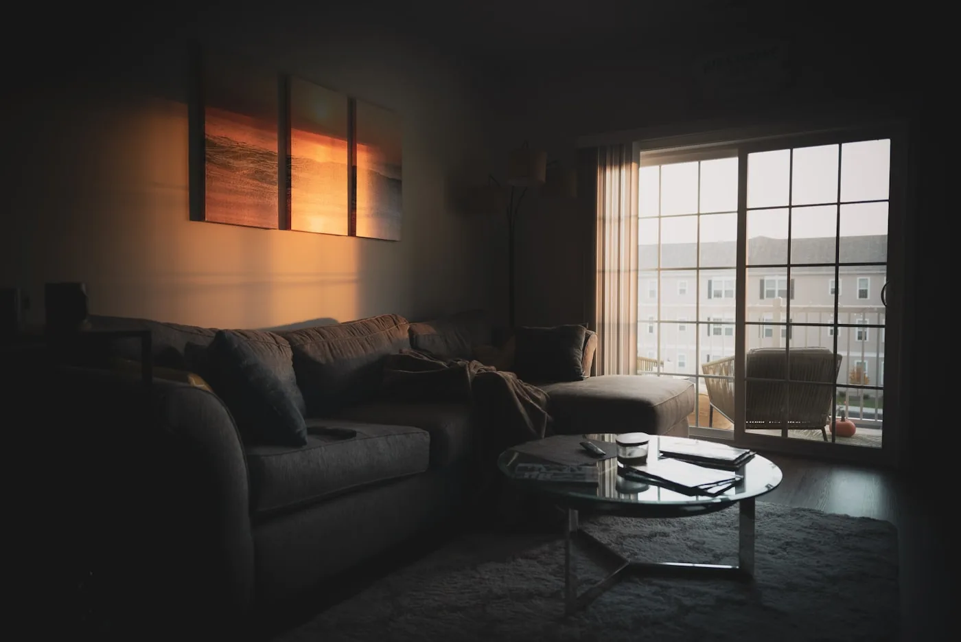 A living room in shade with bright daylight flooding through its window wall