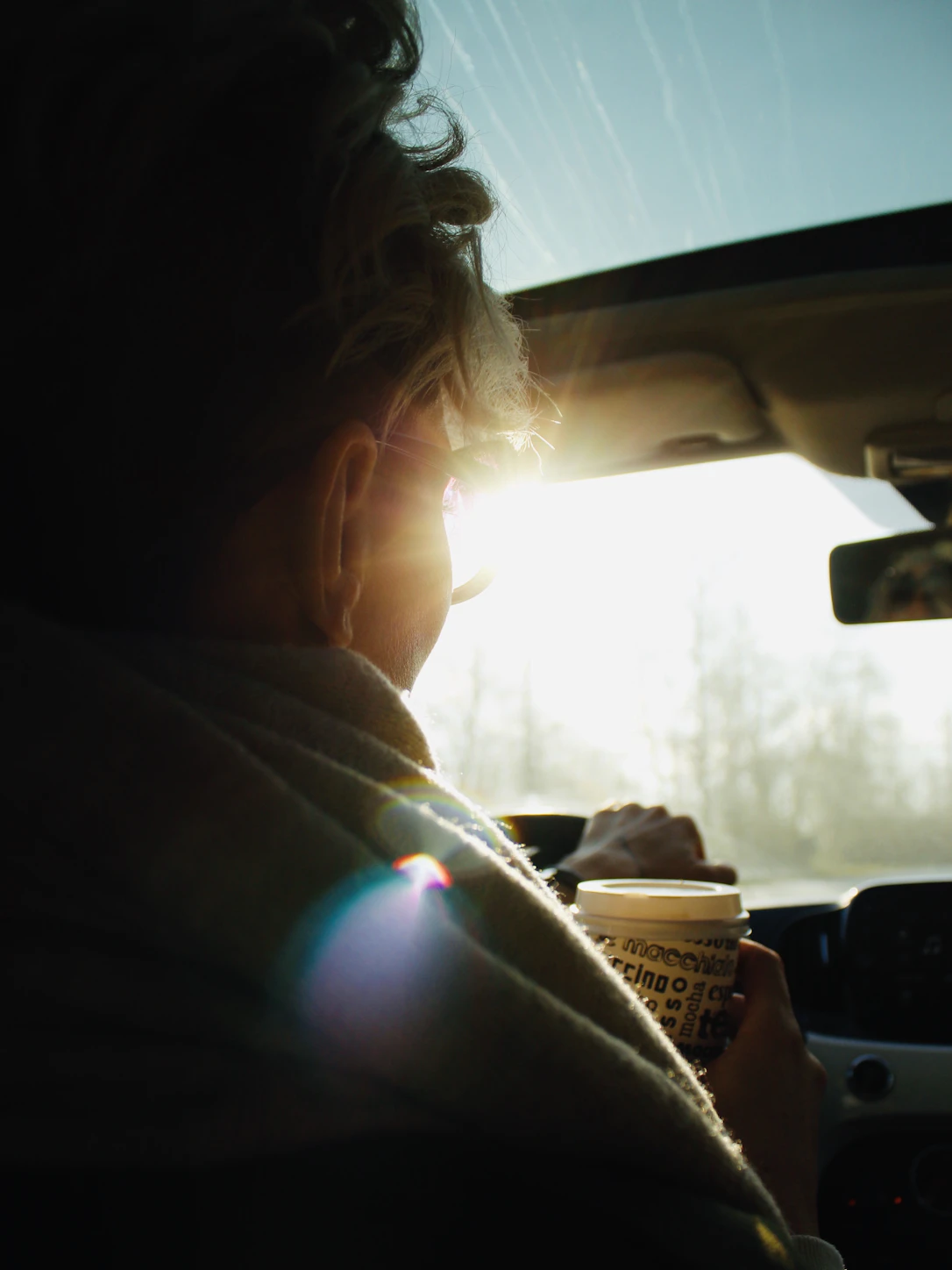 Low sun landing on a driver’s face and hand through the side glass