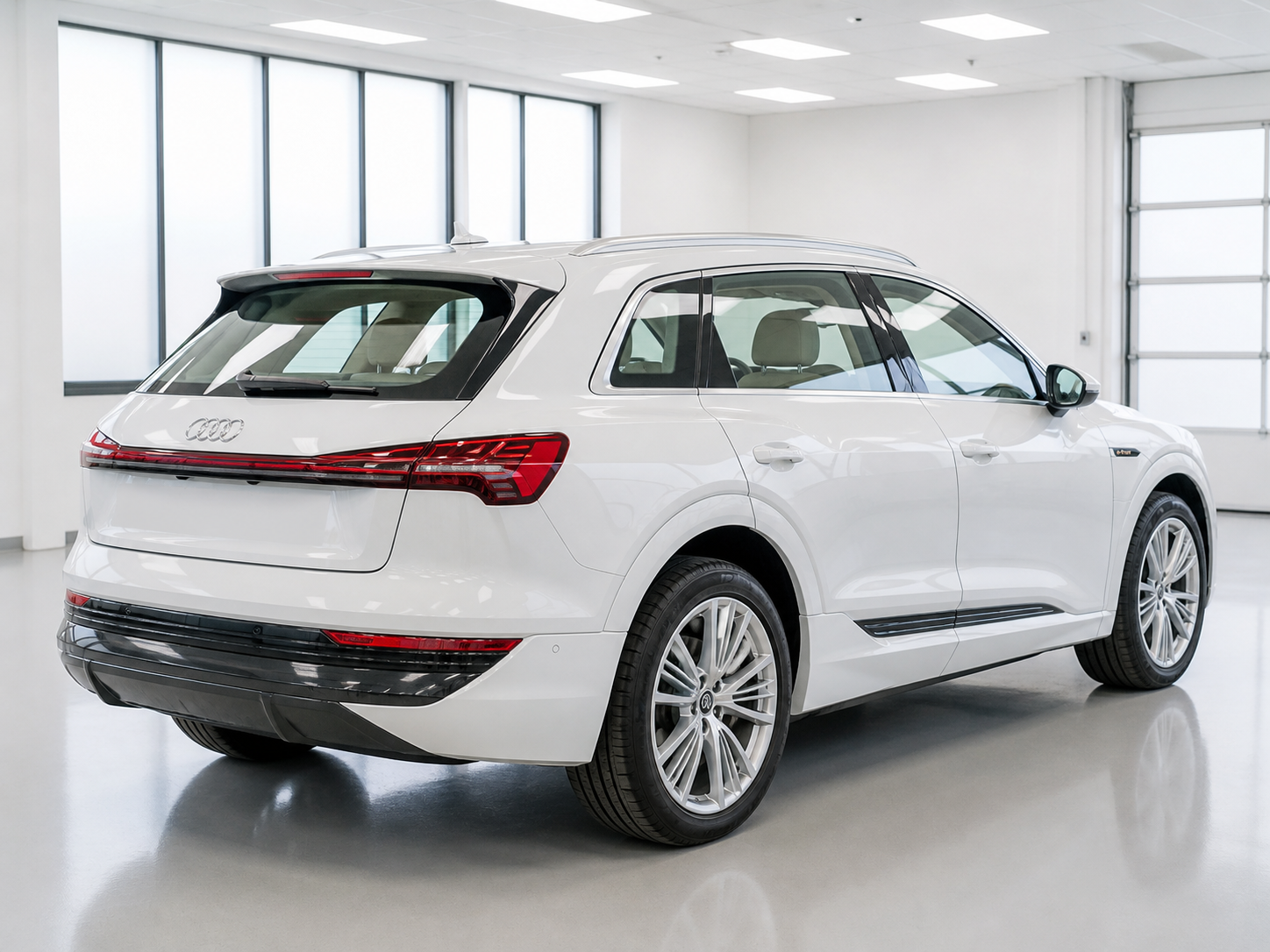 A white Audi e-tron with clear factory glass in a bright tint workshop